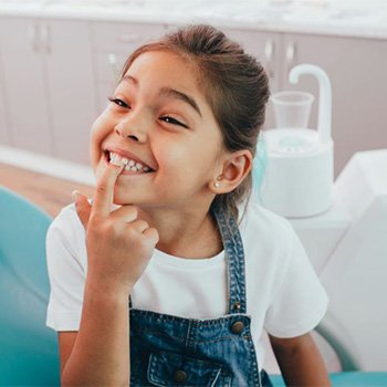 Happy young dental patient pointing at her teeth