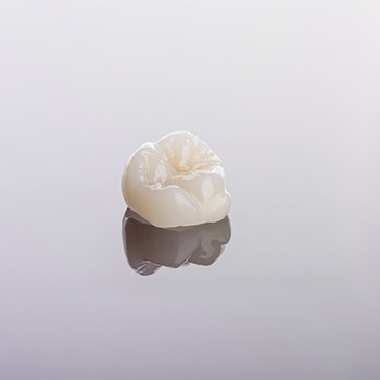 Tooth-colored crown sitting on reflective surface