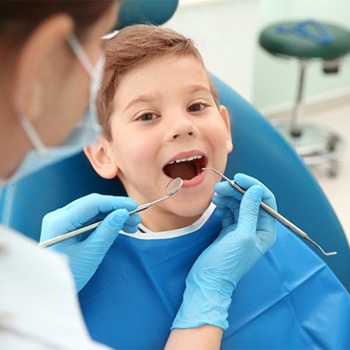 A little boy having his teeth examined to determine where the tooth-colored filling should be placed 